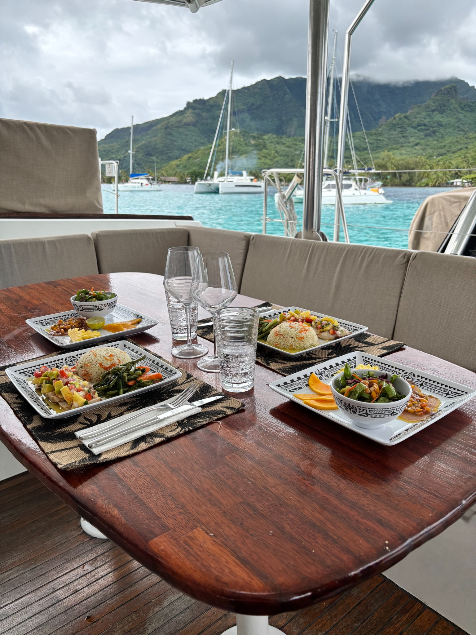 Catered meals set on the catamaran table with Moorea’s lagoon beyond