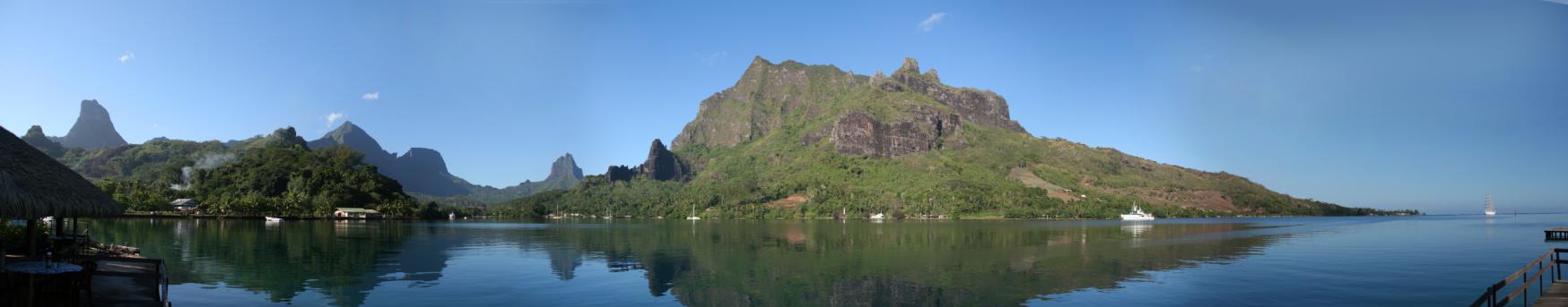 Sunny panoramic view of Cook’s Bay, Moorea, with calm water and mountains beneath a blue sky