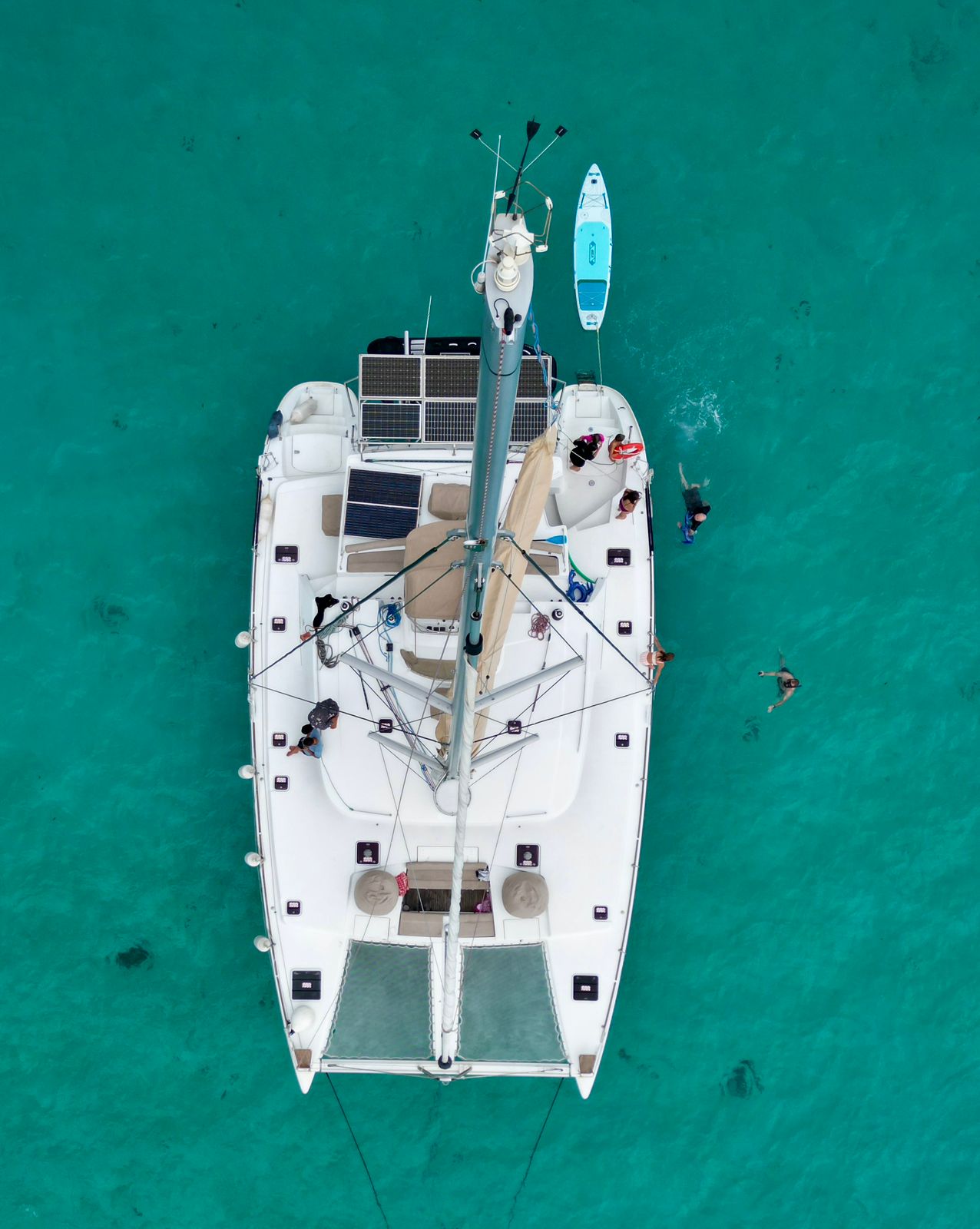 Overhead view of TUATAU V with guests swimming alongside the catamaran