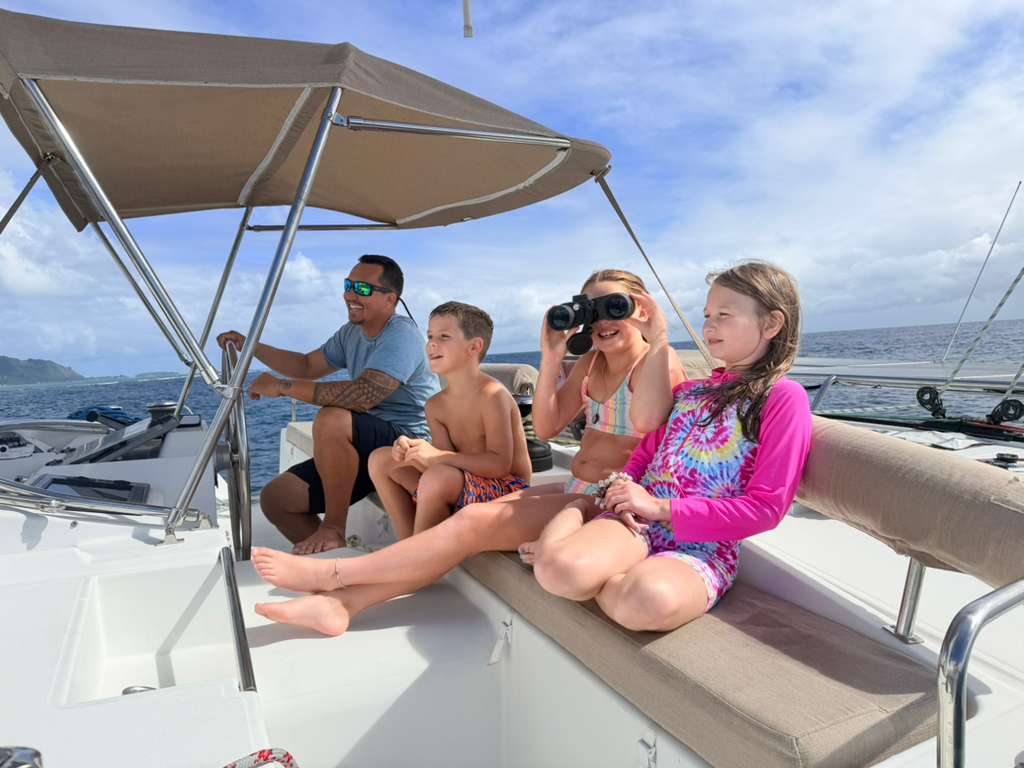 Children enjoying the view beside the captain at the catamaran helm