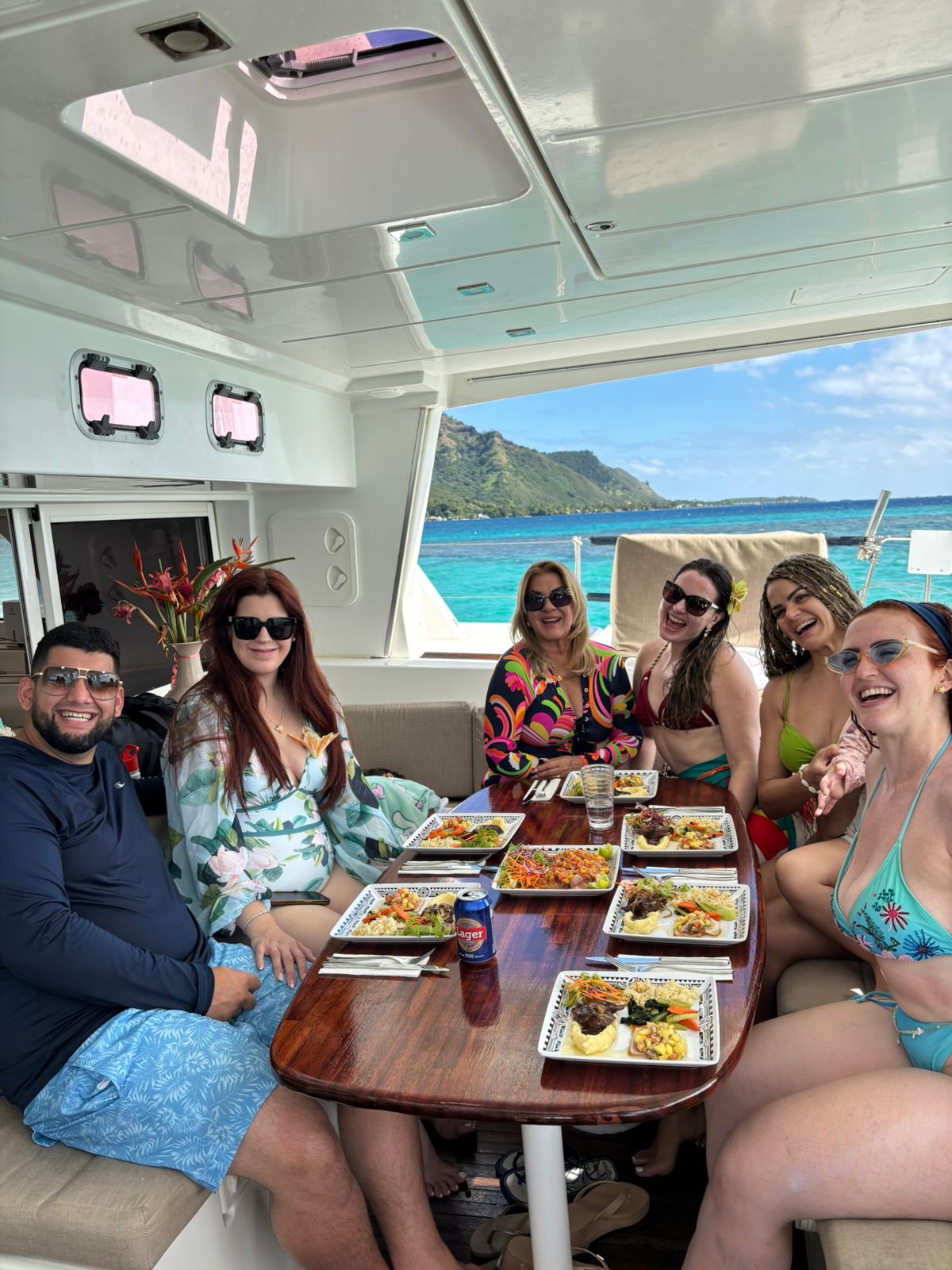 Friends sharing a catered lunch aboard TUATAU V with Moorea’s turquoise lagoon behind