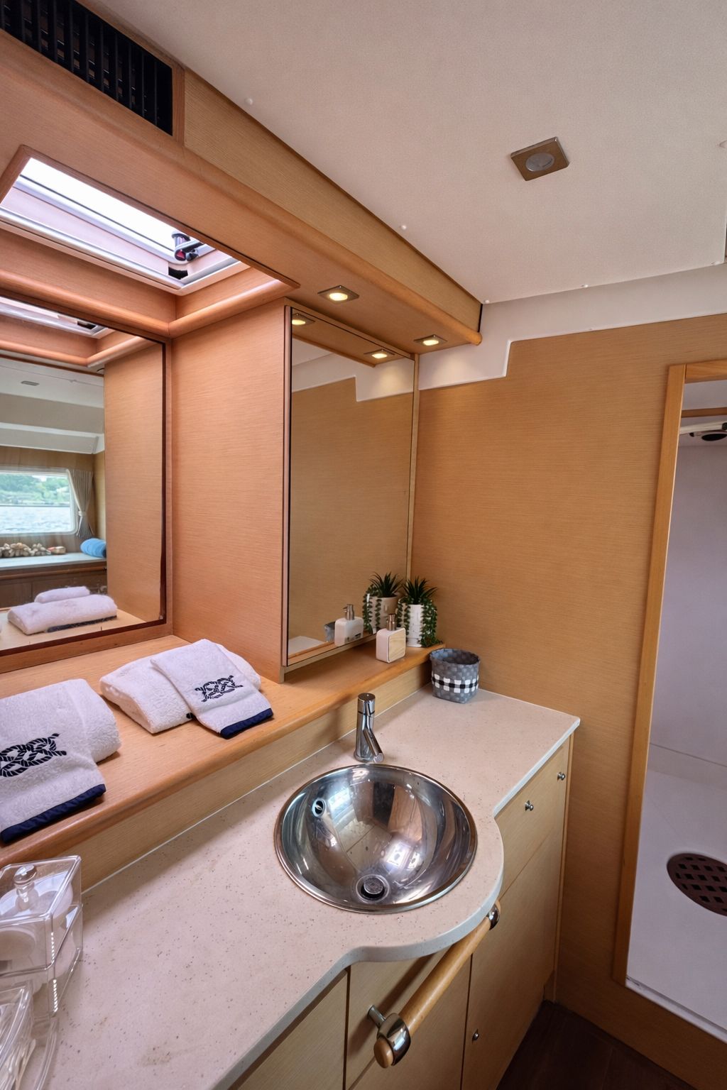 Onboard restroom vanity with a sink, mirrors, and fresh towels